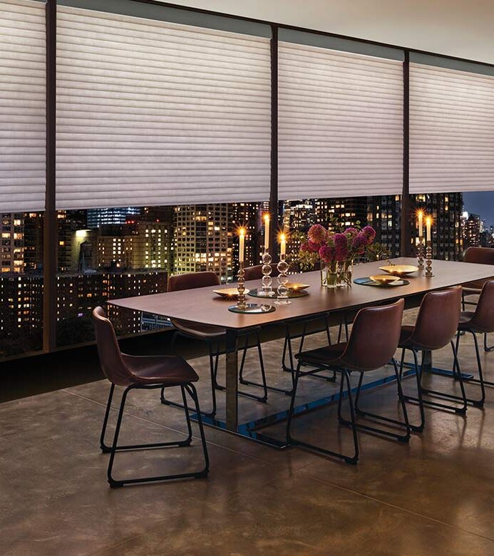 dining room with city building view with aura illuminated honey comb window shades