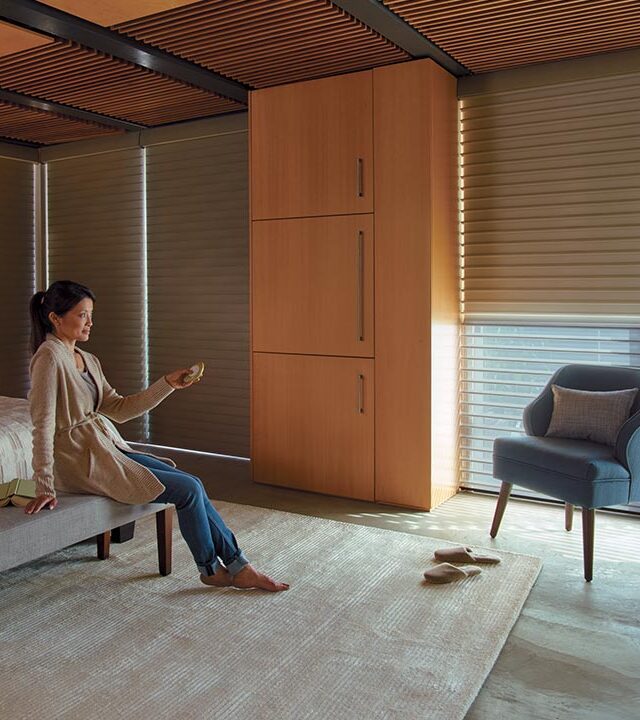 person controlling automatic window shades in bedroom