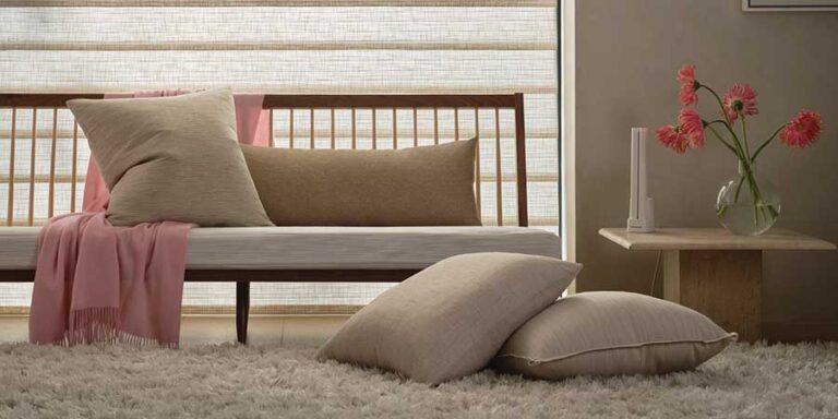 bench infront of window shades floor to ceiling with flowers and pillows