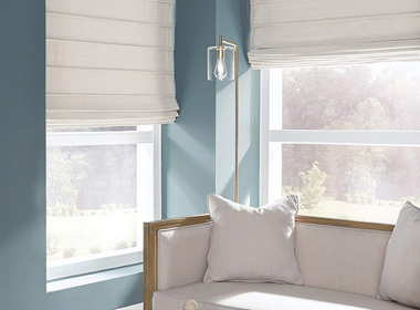 white roman shades in living room with blue walls