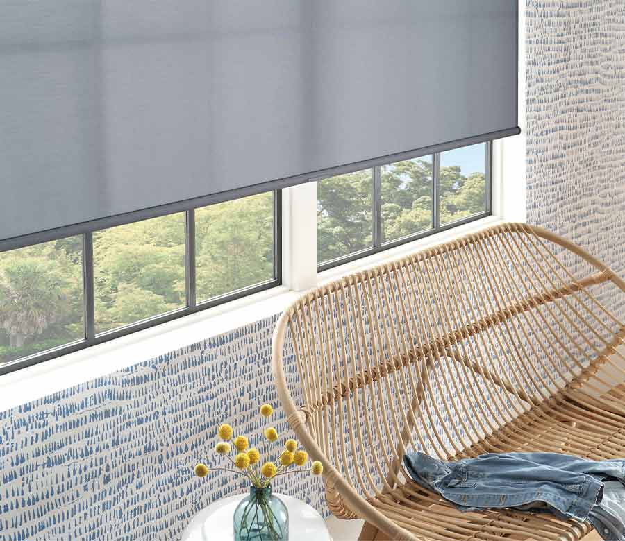 detail of gray roller window shade next to wicker bench