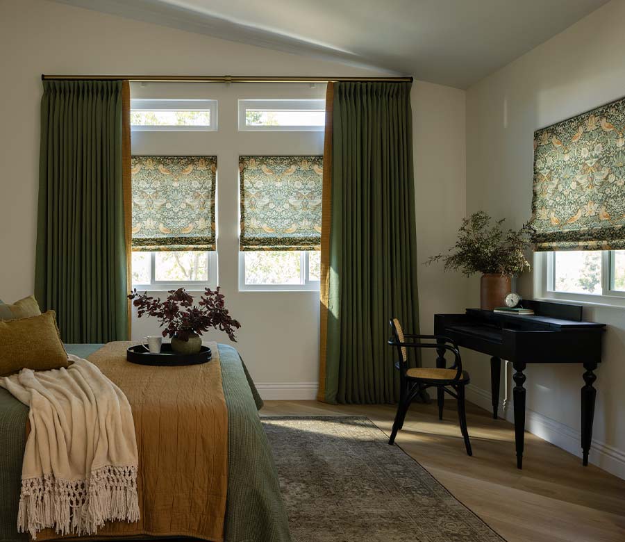 guest bedroom with green botanical patterned roman shades and drapery