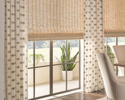 patterned drapery in living room along with natural woven wood shades layered for a bohemian modern look