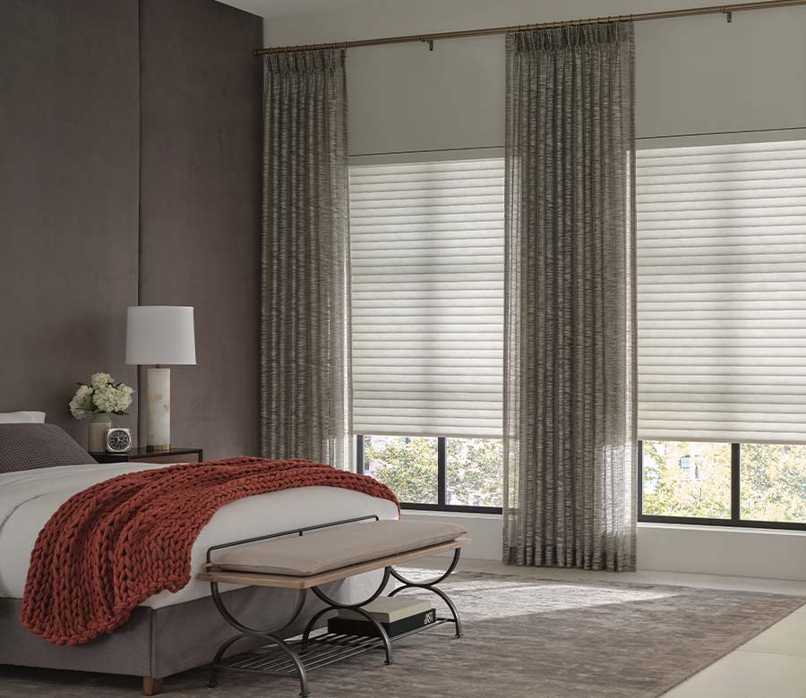 bedroom with neutral window shades and patterned drapery