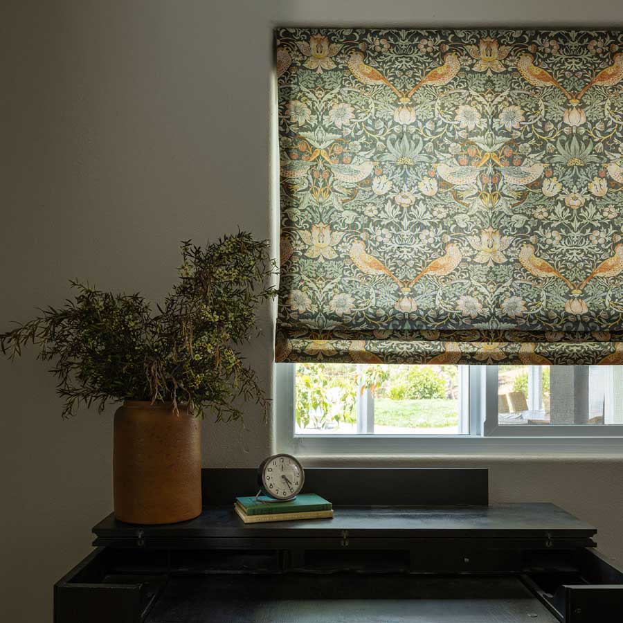 roman shades with birds and botanical patterns covering a bedroom window