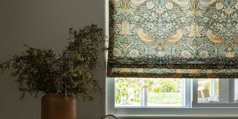 birds and botanical pattern on roman window shades covering a bedroom window
